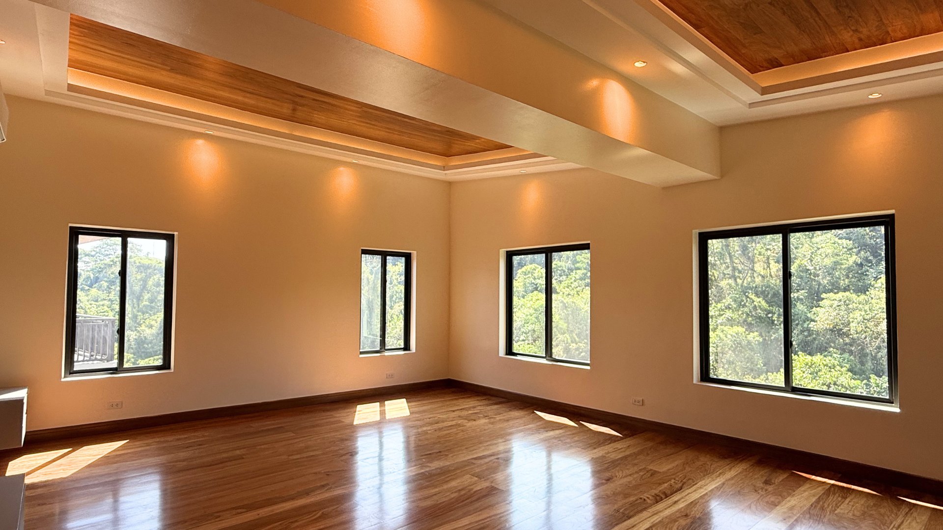 Master bedroom with wood floors, cove lighting, and forest views